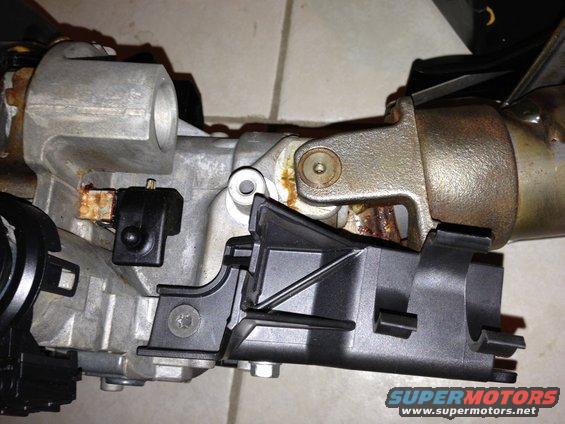 Steering column ignition switch assembly with metal and black plastic components, showing rust and wear
