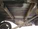 1964 Ford Ranchero - The undercarriage of a vehicle displays significant rust on its structural components and bed.
