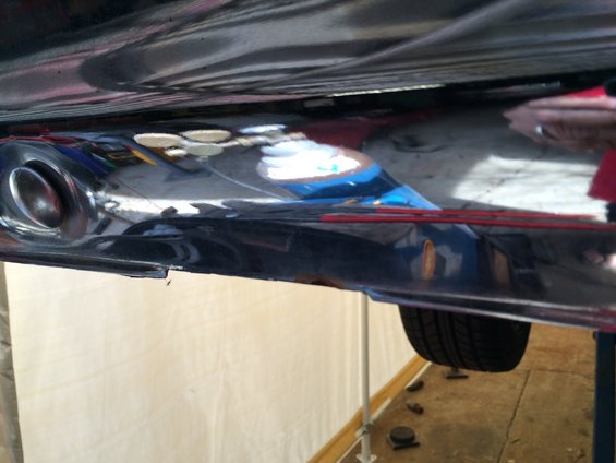 Underside view of a chrome exhaust pipe and part of the vehicle's undercarriage