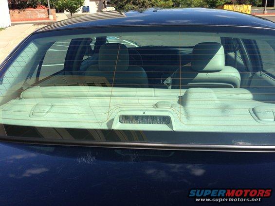 Rear window and interior of a dark sedan. The SUPERMOTORS watermark is visible at the bottom right