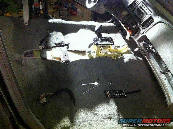 Interior of a car with the center console removed, showing the gear shifter and wiring