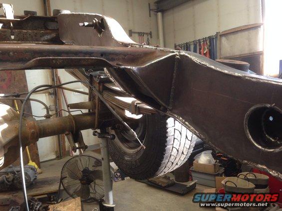 close-up of vehicle frame, leaf springs, and rear axle assembly on a lift
