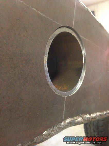Close-up of a thick metal plate with a circular hole and visible weld seams