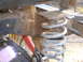 1978 Ford Bronco - This image shows a close-up view of a vehicle's suspension system, focusing on a coil spring and shock absorber.