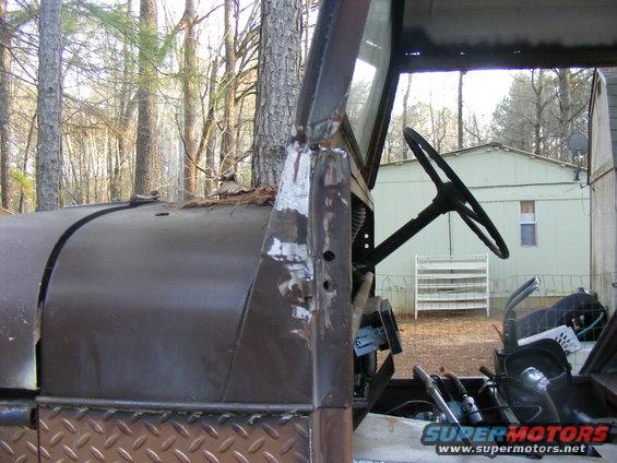 View of an old vehicle's interior showing the steering wheel, dashboard, and part of the hood. Diamond plate is visible on the lower body