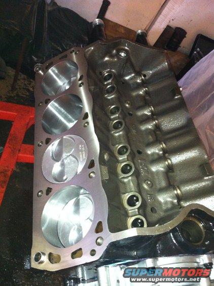Engine block with pistons visible in cylinders. Some text is stamped on the block