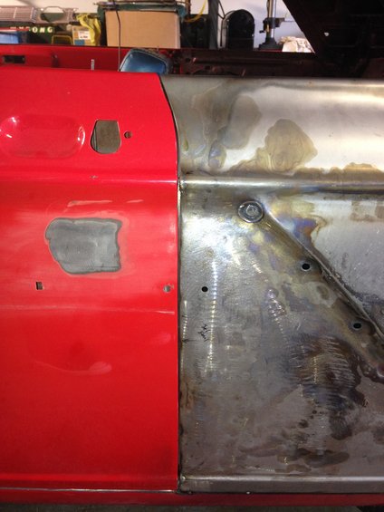 Red car door panel next to bare metal section with visible welds and bolt