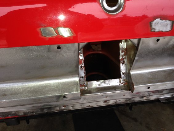 Red car body panel with visible welding patches and cut-out section revealing inner structure