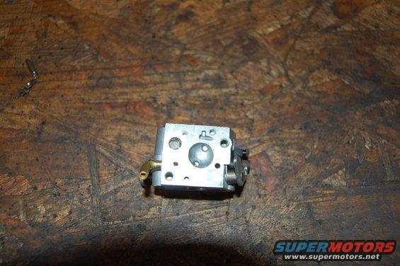 small metal carburetor with brass fitting on a wooden surface