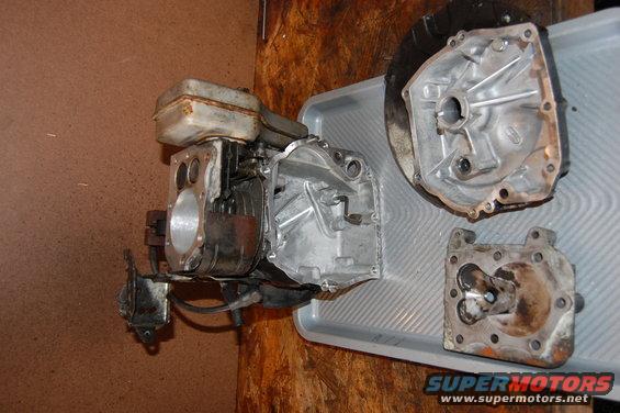 Engine block and two other metal parts laid out on a gray tray