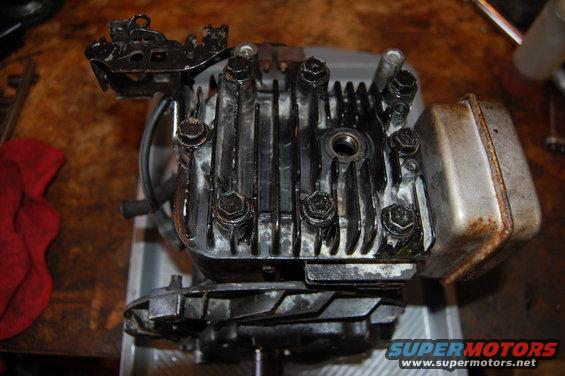 Engine cylinder head with fins, bolts, and a muffler attached