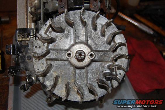Close-up of a metal engine flywheel with fins. Some text is visible on the surface
