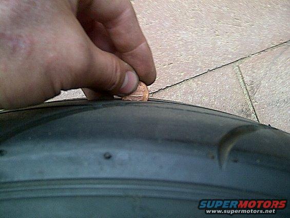 Close-up of a hand holding a penny to measure tire tread depth