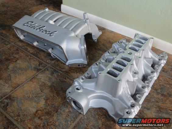 Two silver Edelbrock intake manifolds on a tiled floor