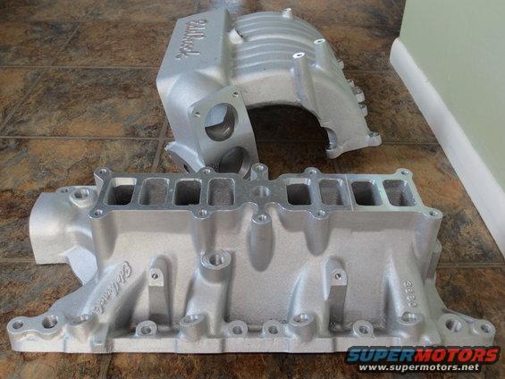 Two silver Edelbrock intake manifolds on a tiled floor