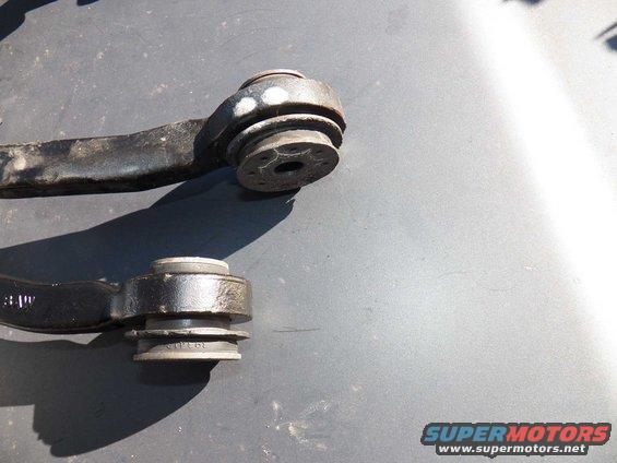 Two car suspension control arm bushings, one with white marks, the other with visible part numbers