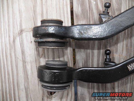 Two black metal front suspension control arms with rubber bushings and ball joints, one above the other