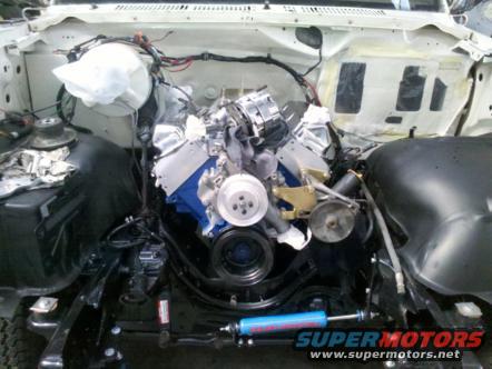 1982 Ford Bronco engine bay with engine installed, showing alternator, pulleys, and wiring