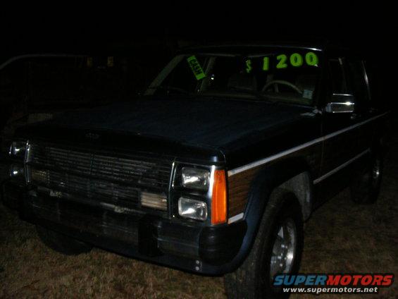 Dark blue Jeep Cherokee Wagoneer with wood paneling. Price tag in window says $1200