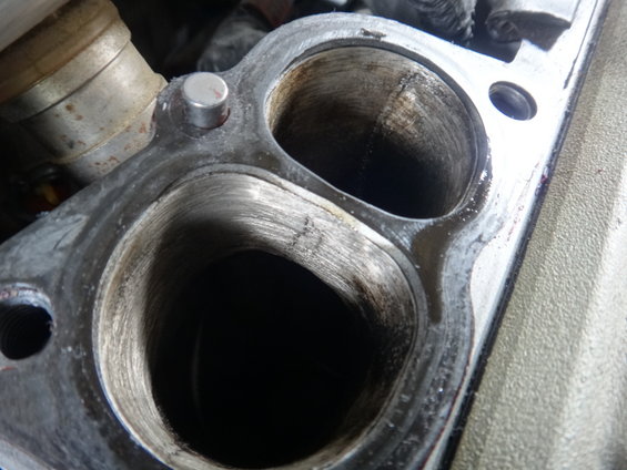 Close-up of an engine intake manifold with two ports showing wear and carbon buildup