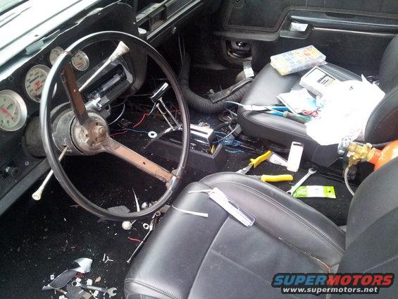 1973 Ford Ranchero interior with aftermarket gauges, tools, and wiring scattered on the floor and seats