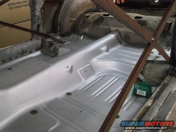 car interior floor pan with metal bracing, looks like a 1967 Mustang undergoing restoration