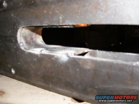 Close-up of a metal part with a cut-out and visible welds
