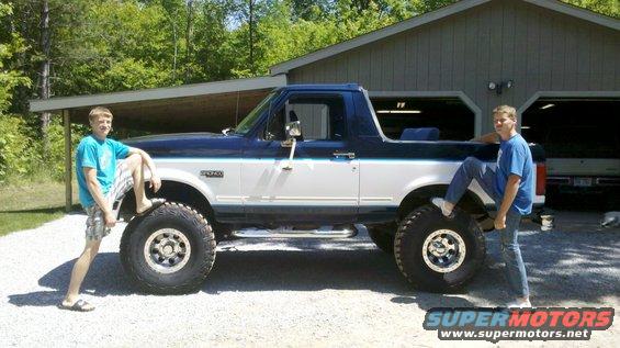 Two-tone blue and white Ford Bronco with lifted suspension and large tires