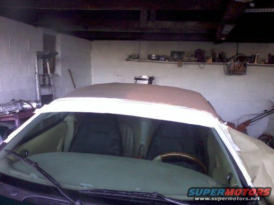 Car interior showing seats and dashboard, with a convertible top covered in brown fabric and white tape