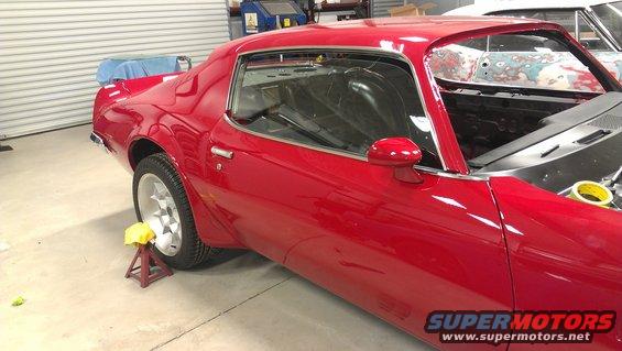 Red 1970s Pontiac Firebird in garage, hood open