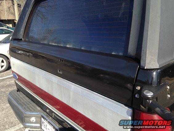 Rear of black and silver SUV with red stripe and tinted window