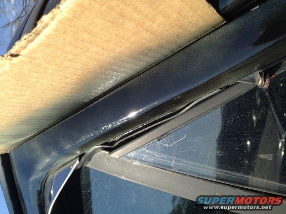 Close-up of car door frame with wood paneling attached, showing weather stripping and a reflection in the glass