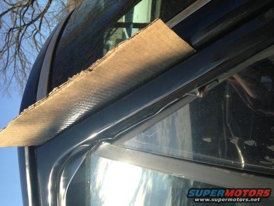 Cardboard protecting black window trim on a vehicle
