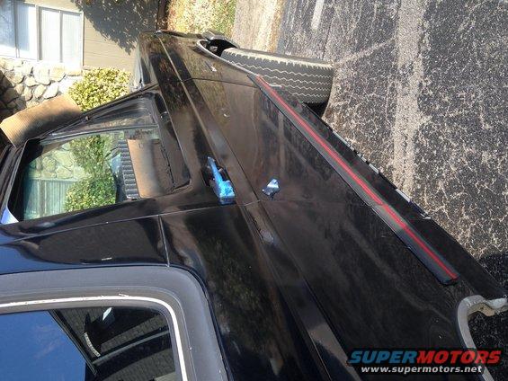 Black SUV side view, spare tire visible in rear, red stripe on body panel