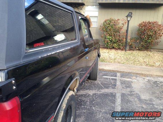 Side view of a black SUV parked in a lot. Red sticker on the rear window