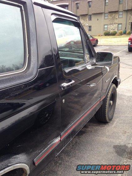 Black 1990 Ford Bronco side view, showing door handle, side trim, and rear wheel