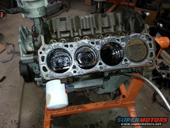 Engine block with pistons visible, on an orange stand