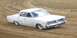 1969 Lincoln Continental - A white 1963 Pontiac Catalina sedan navigates a dirt track, its distinctive grille and whitewall tires.