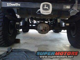 Rear axle, suspension, and fuel tank of a lifted truck with Draw-Tite and John Deere decals