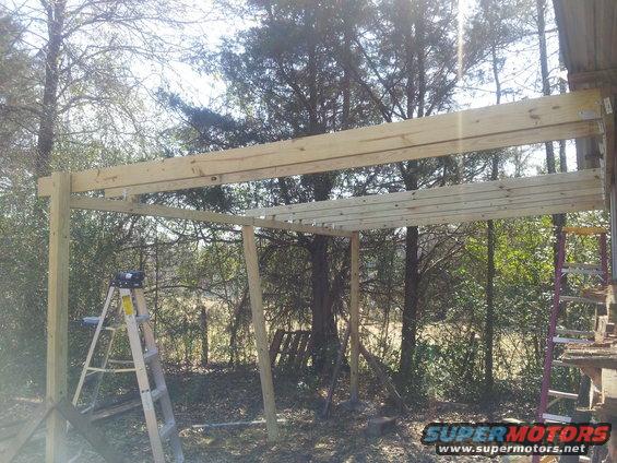 Wooden frame for a structure under construction with a ladder leaning against a post