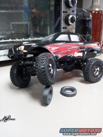 Black remote control monster truck with red graphics, large tires, and two spare rings