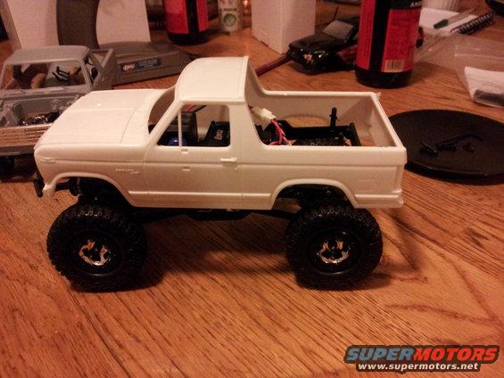 White RC Bronco model on a wooden table, with another model in the background