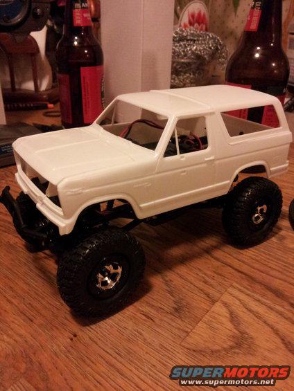 White model SUV with black tires and chrome rims on a wooden surface