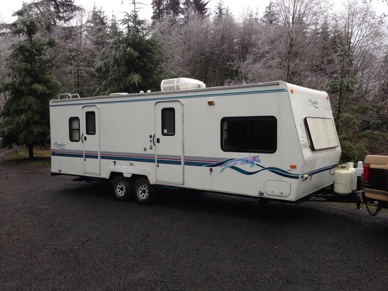 travel trailer parked outside with trees in the background
