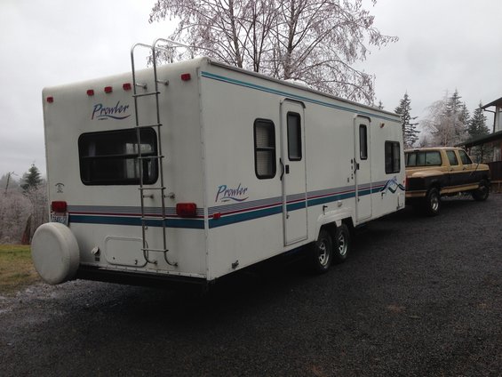 Rear view of a Prowler travel trailer and a tan and brown pickup truck