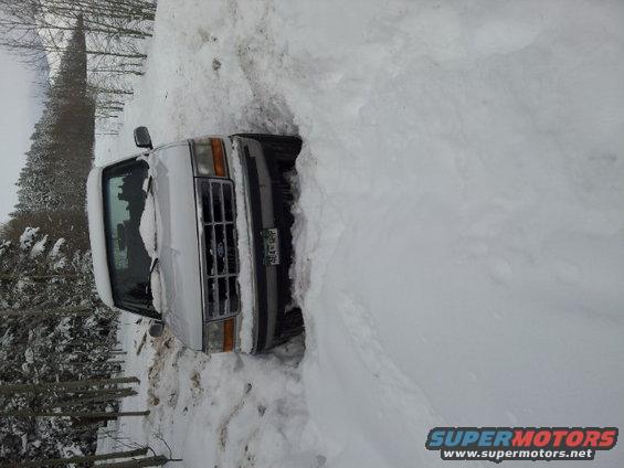 White Ford truck stuck deep in snow, front end visible