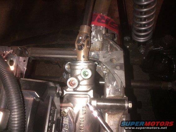 Steering column U-joint connected to a gearbox, with visible metal brackets and a black hose