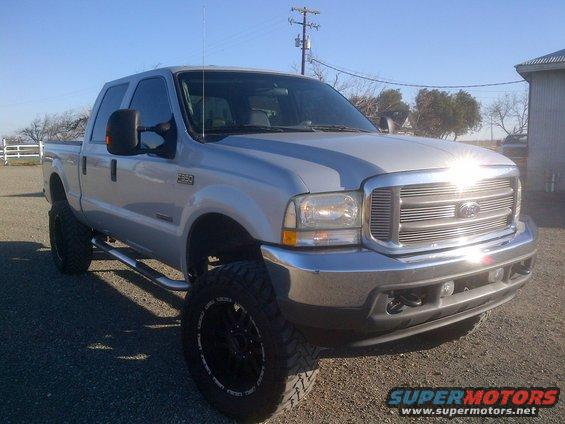 Silver Ford F-350 pickup truck, lifted with large tires, seen from a 3/4 front angle