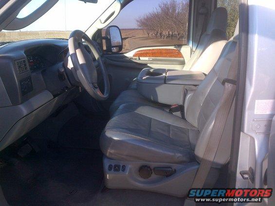 Interior of a truck showing the driver's seat, dashboard, and center console. Wood trim accents are visible on the door