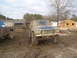1978 Ford Bronco - A muddy 1978 Ford Bronco sits in a dirt lot next to another pickup truck, with houses and construction in the background.